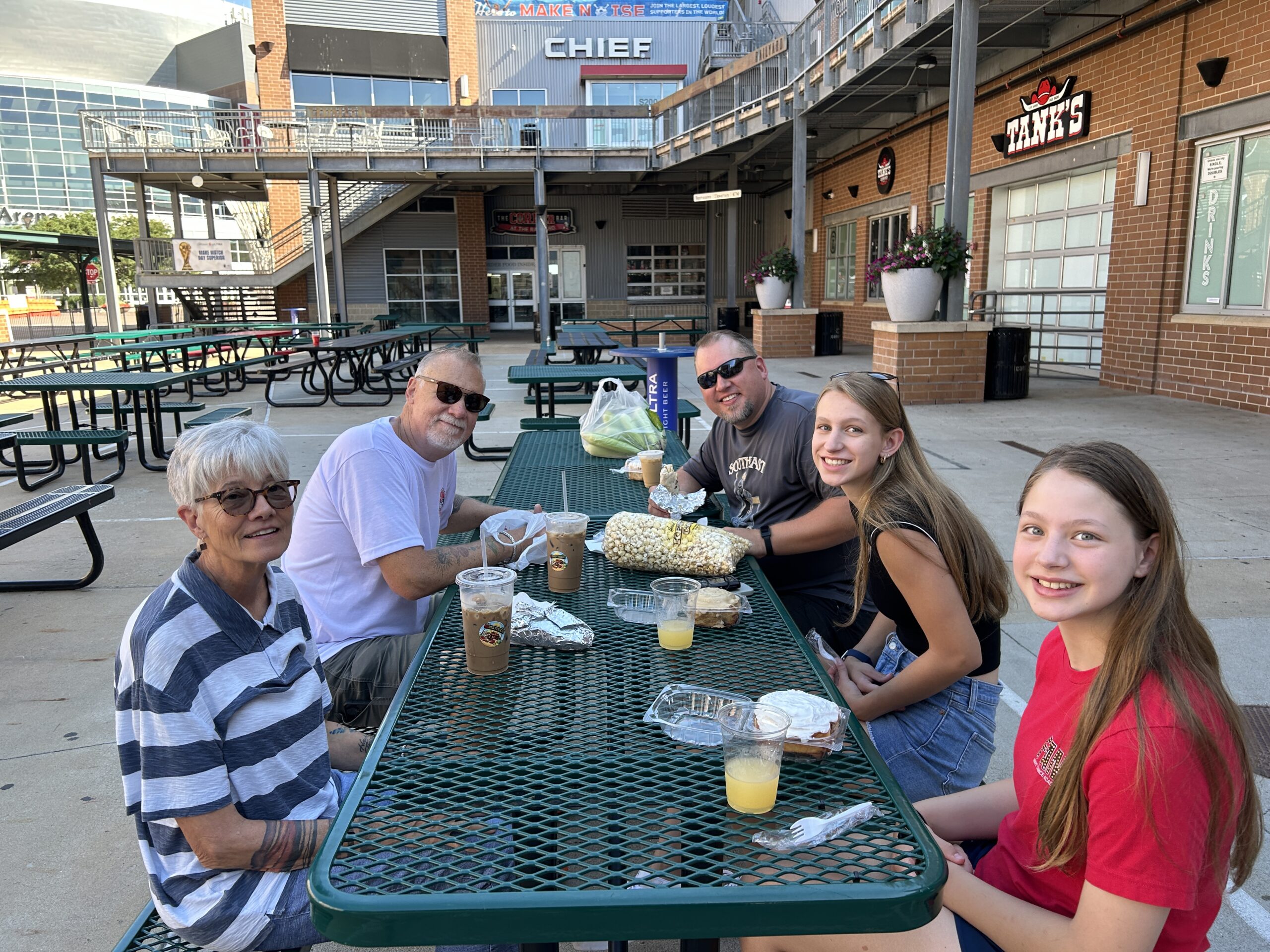 Family enjoying coffee and cinnamon rolls together at an outdoor patio during a summer farmer's market