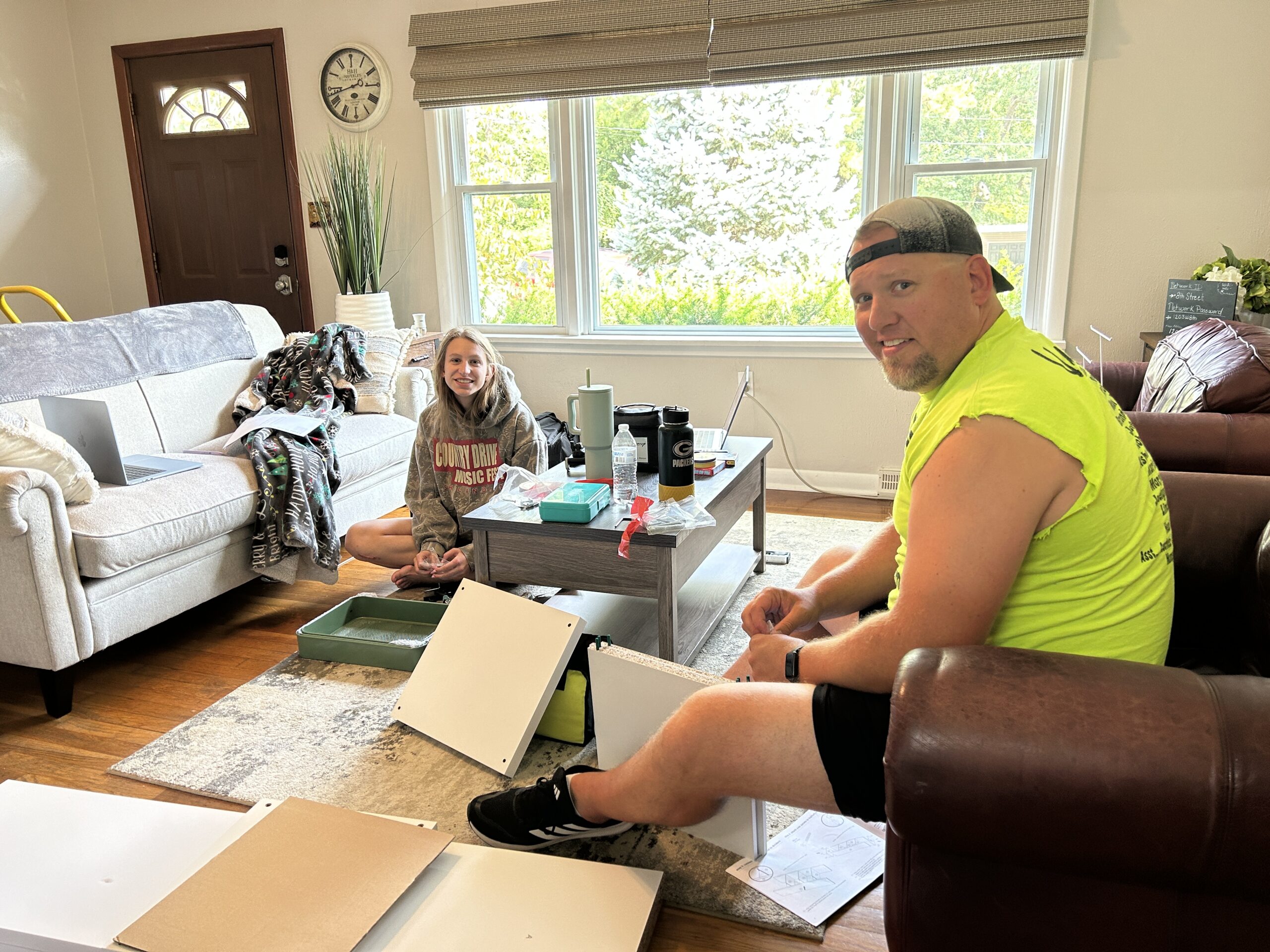 Dad and daughter assemble furniture in an airbnb living room during move-in day.