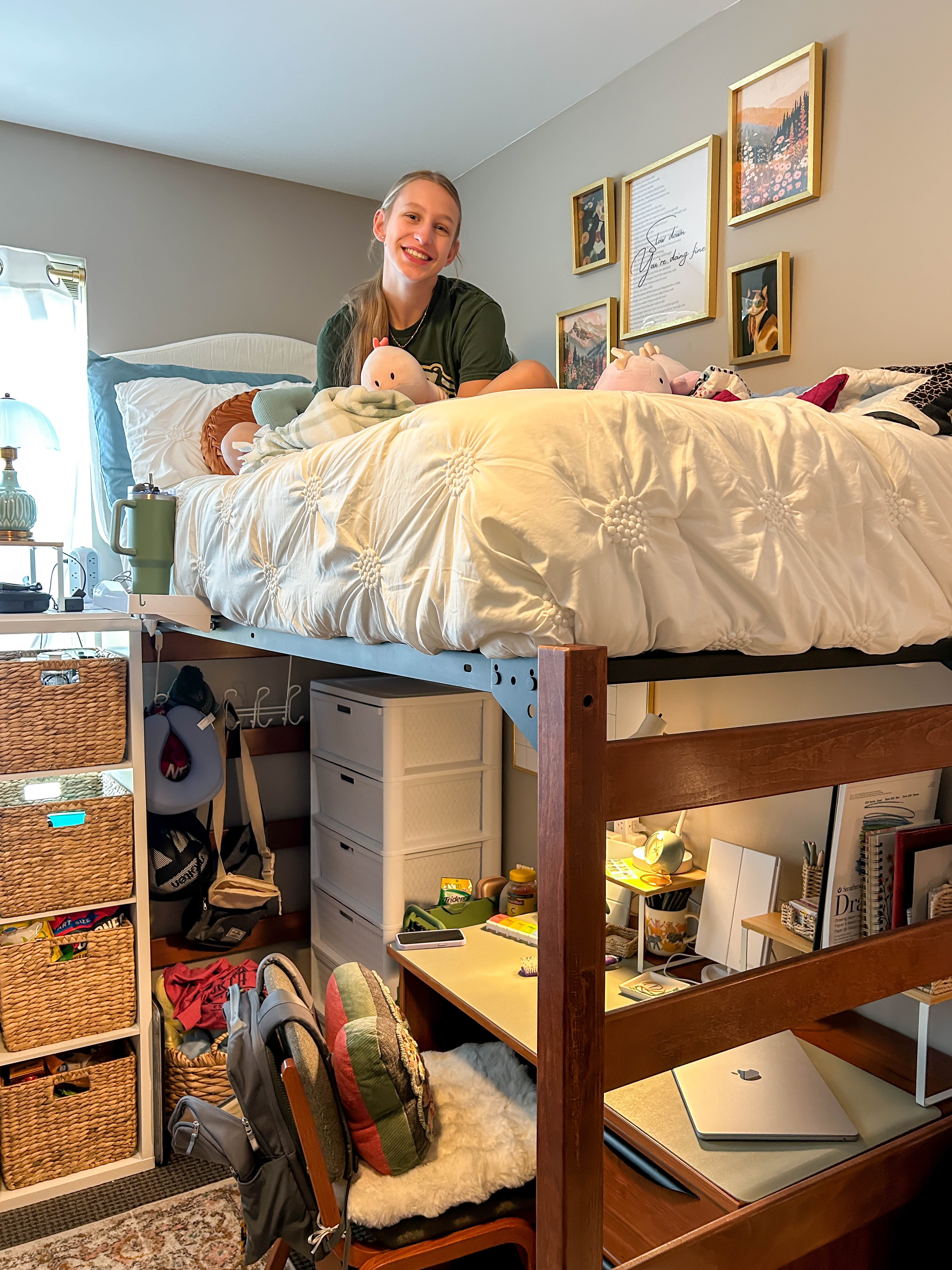 College student sitting on her decorated lofted bed after getting settled into her new college dorm bedroom.