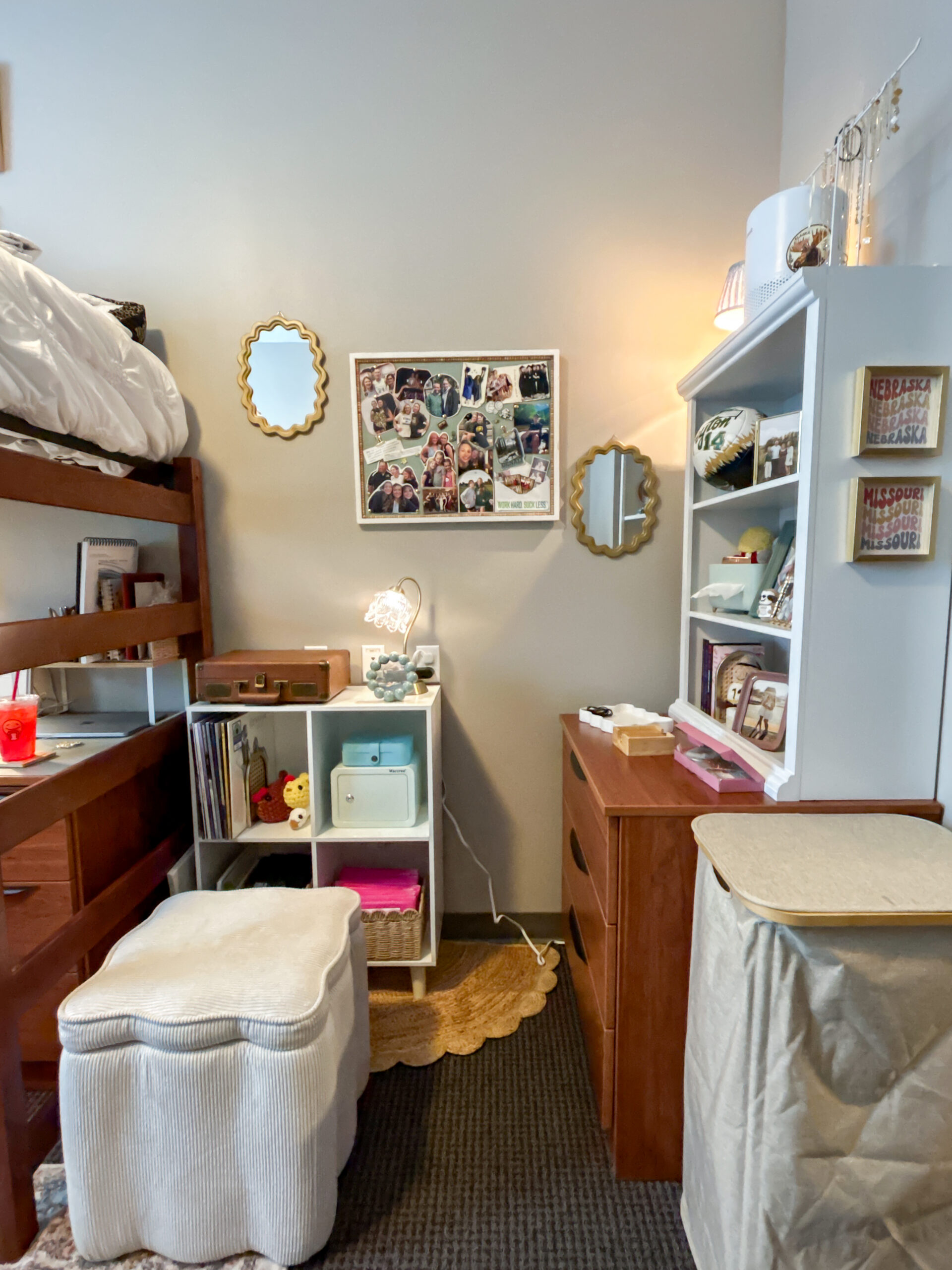 Girl's College dorm bedroom storage area with a cube organizer, dresser, bookshelf, ottoman, mirrors, and personal decor.