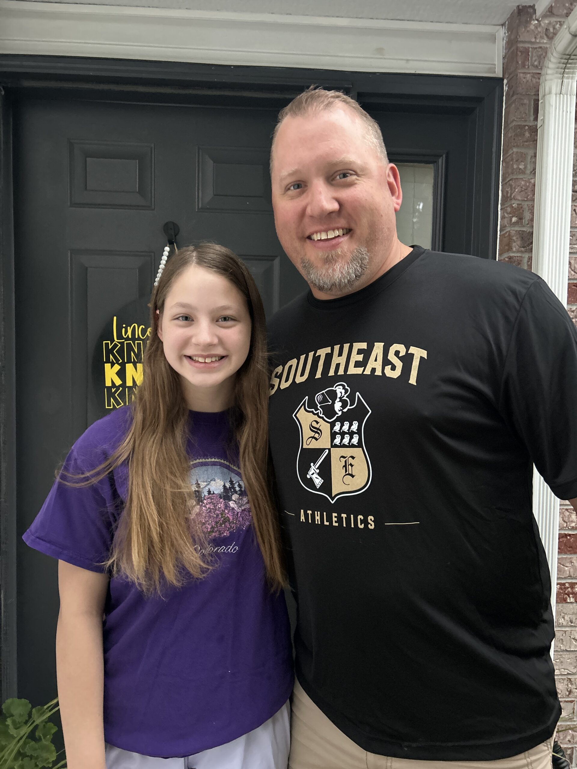 Father and daughter smiling together outside their home before heading to school.