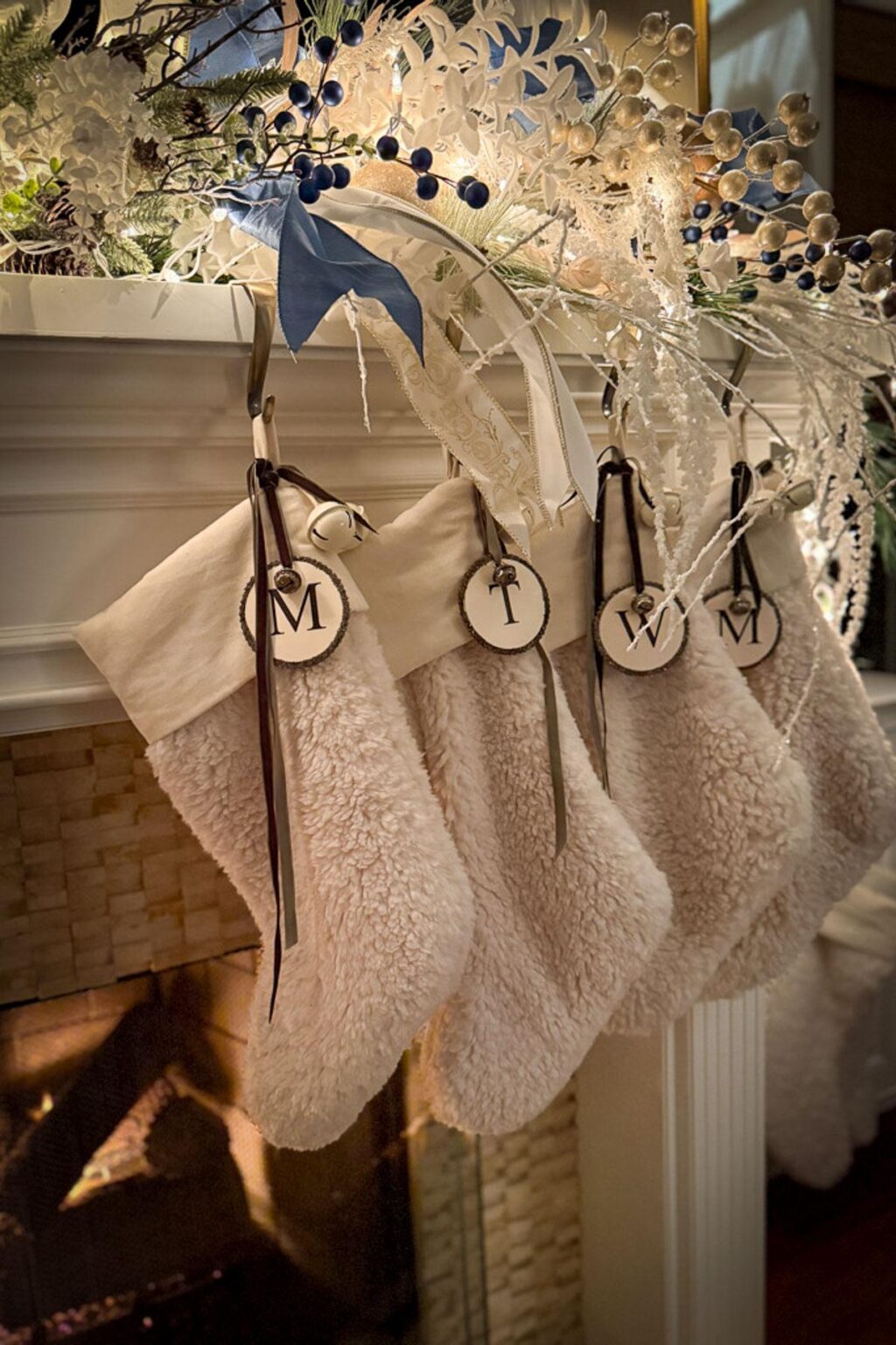 Blue and white holiday color palette with white Christmas stockings, blue ribbon, greenery, berries, and twinkle lights.