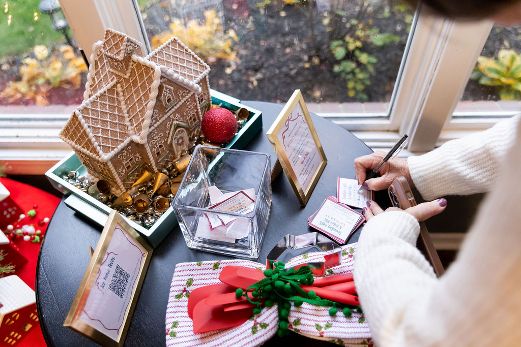 Holiday Open House guest filling out a giveaway entry beside a gingerbread house and festive Christmas decorations.