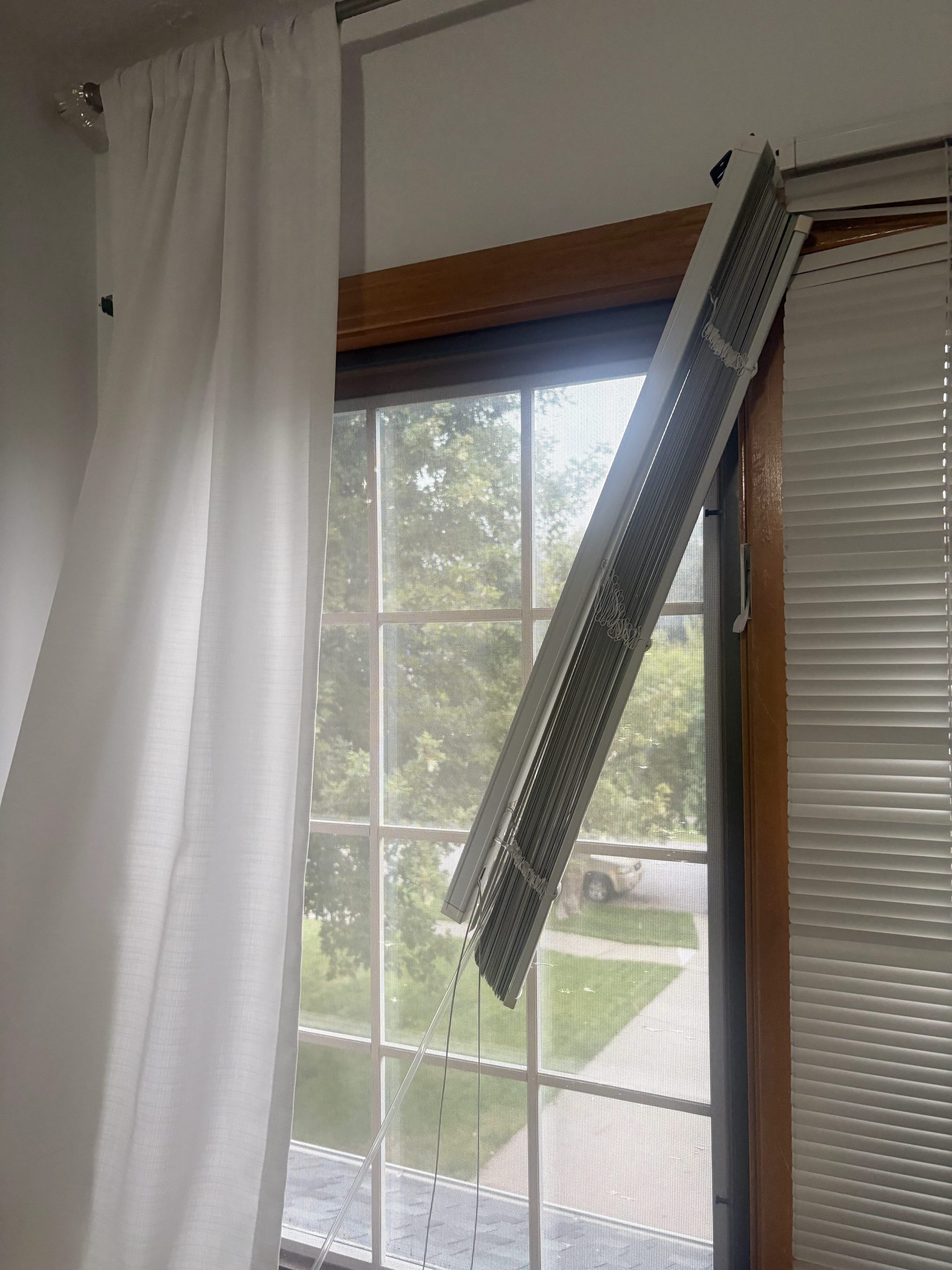 photo of a broken blind hanging from a window