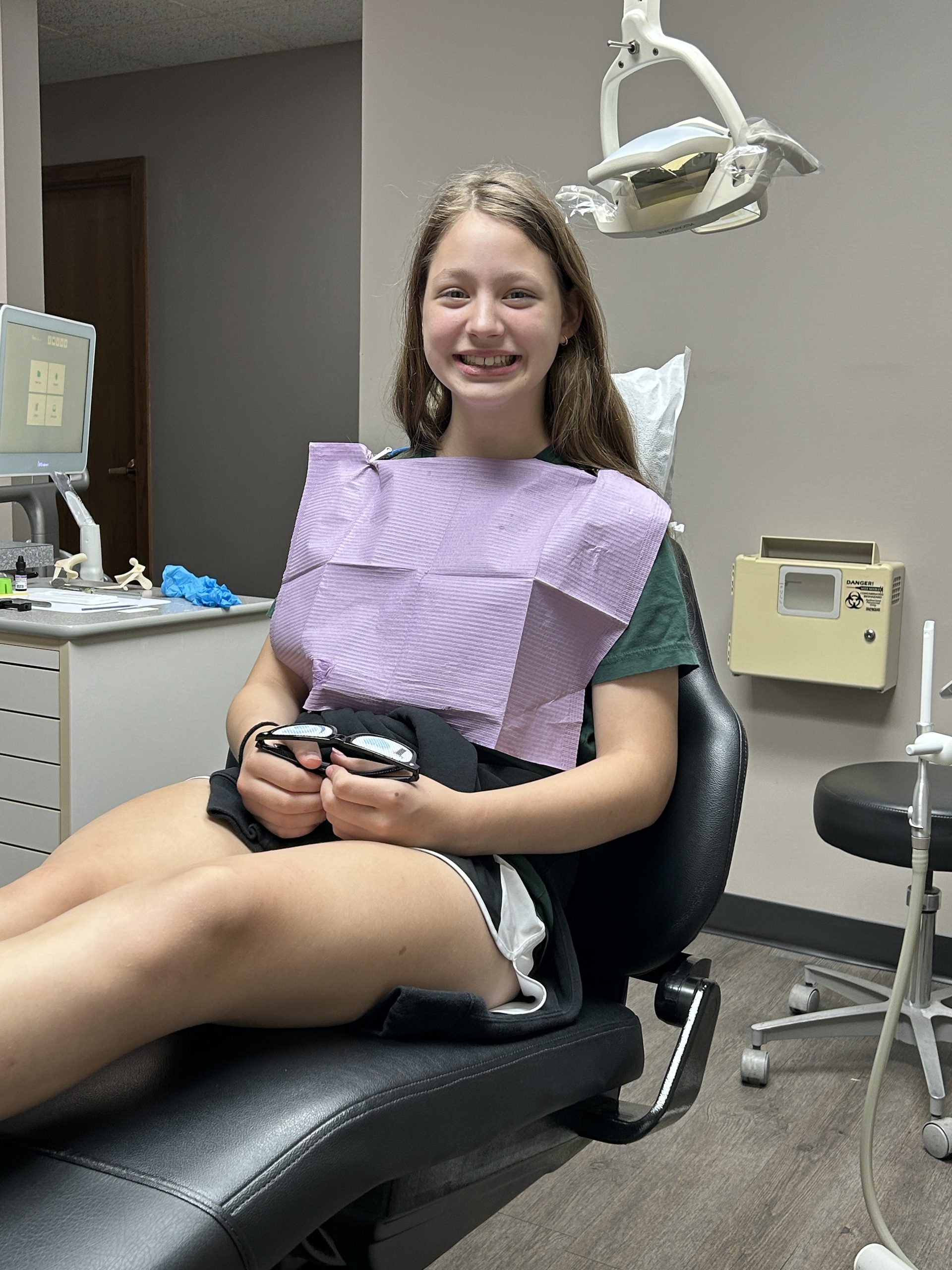 Young girl smiling in the orthodontist chair before getting braces.