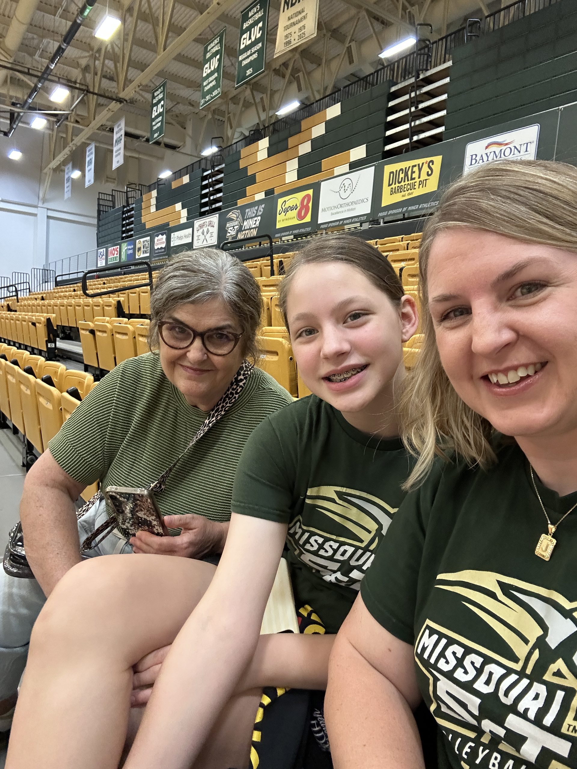 Three generations sitting together in the stands at a Missouri S&T volleyball match.