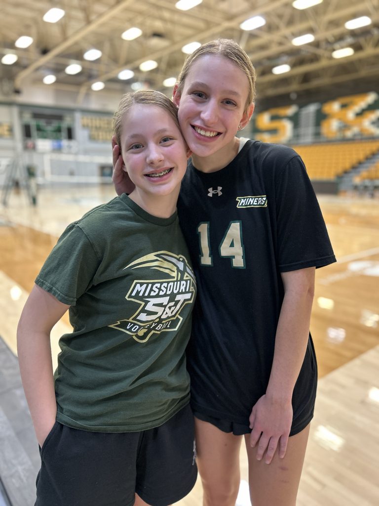 Sisters smiling and hugging on the volleyball court after a Missouri S&T home match.