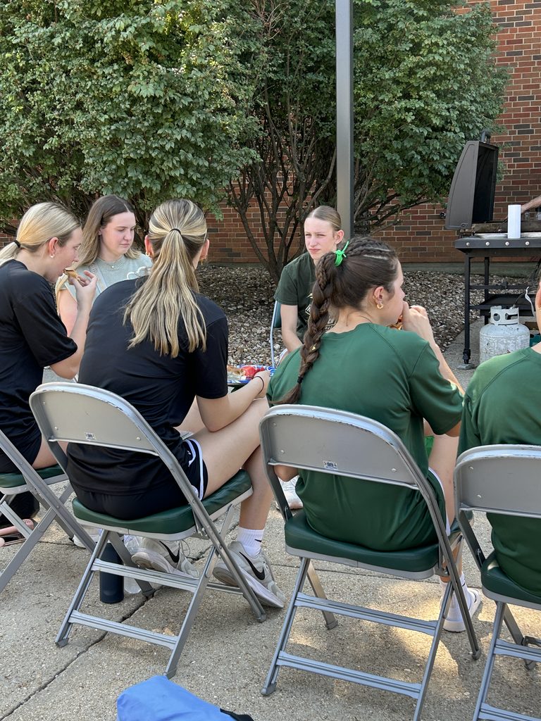 Missouri S&T volleyball players sitting together and eating at an outdoor team tailgate