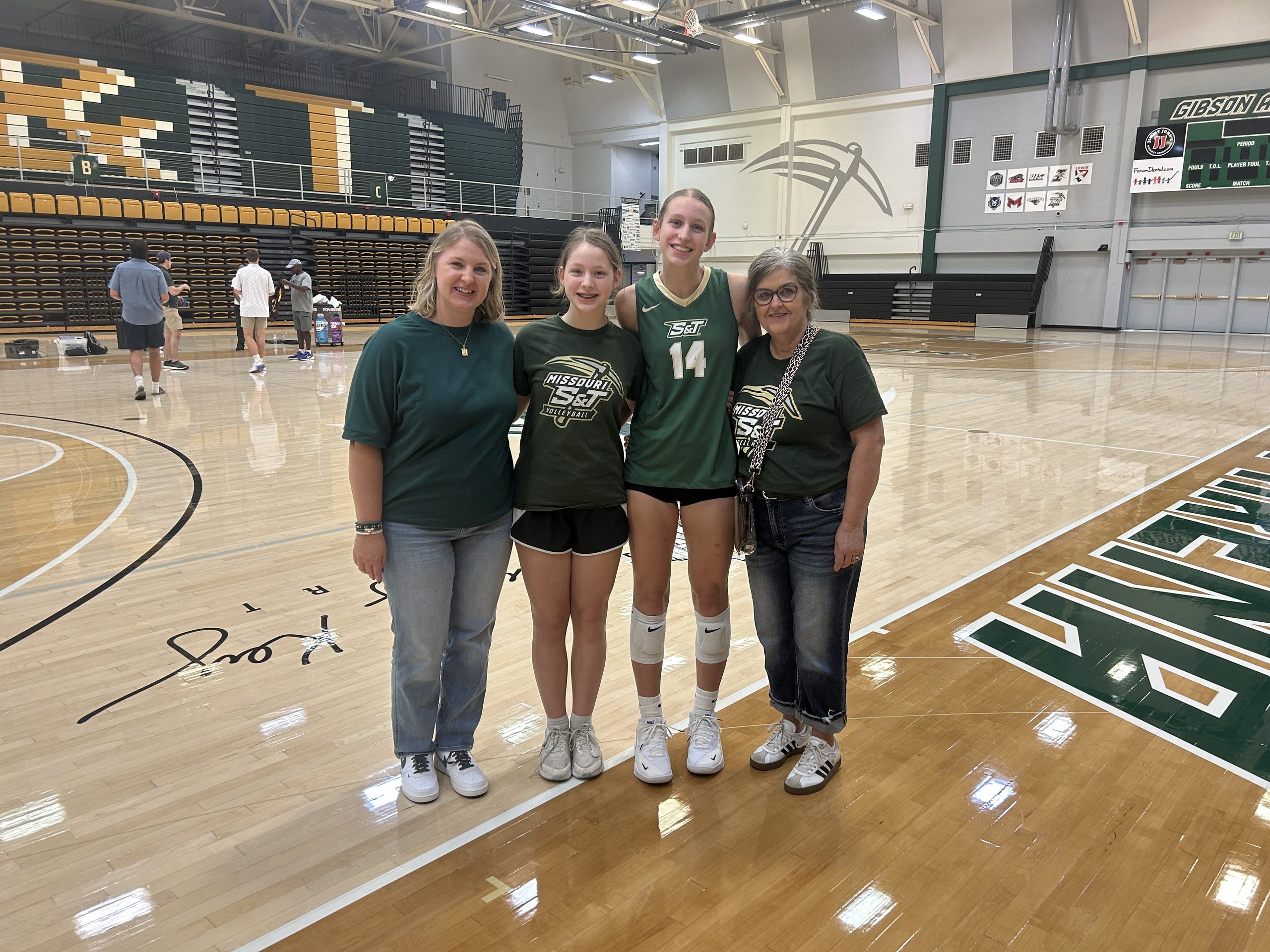 Four family members posing together on the court after a Missouri S&T volleyball matc