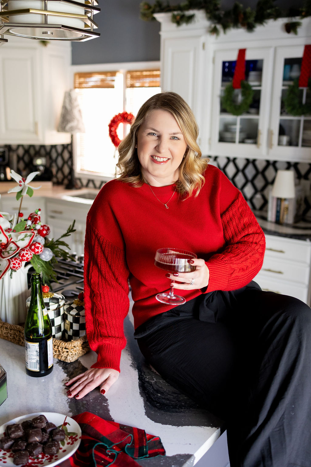 Jen holding a festive holiday drink in a decorated Christmas kitchen.