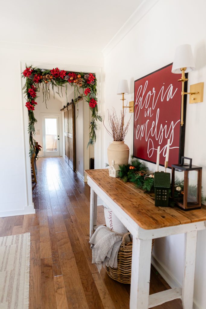 Red and black holiday color palette in a Christmas entryway with red poinsettias, greenery, black lanterns, and warm gold accents.