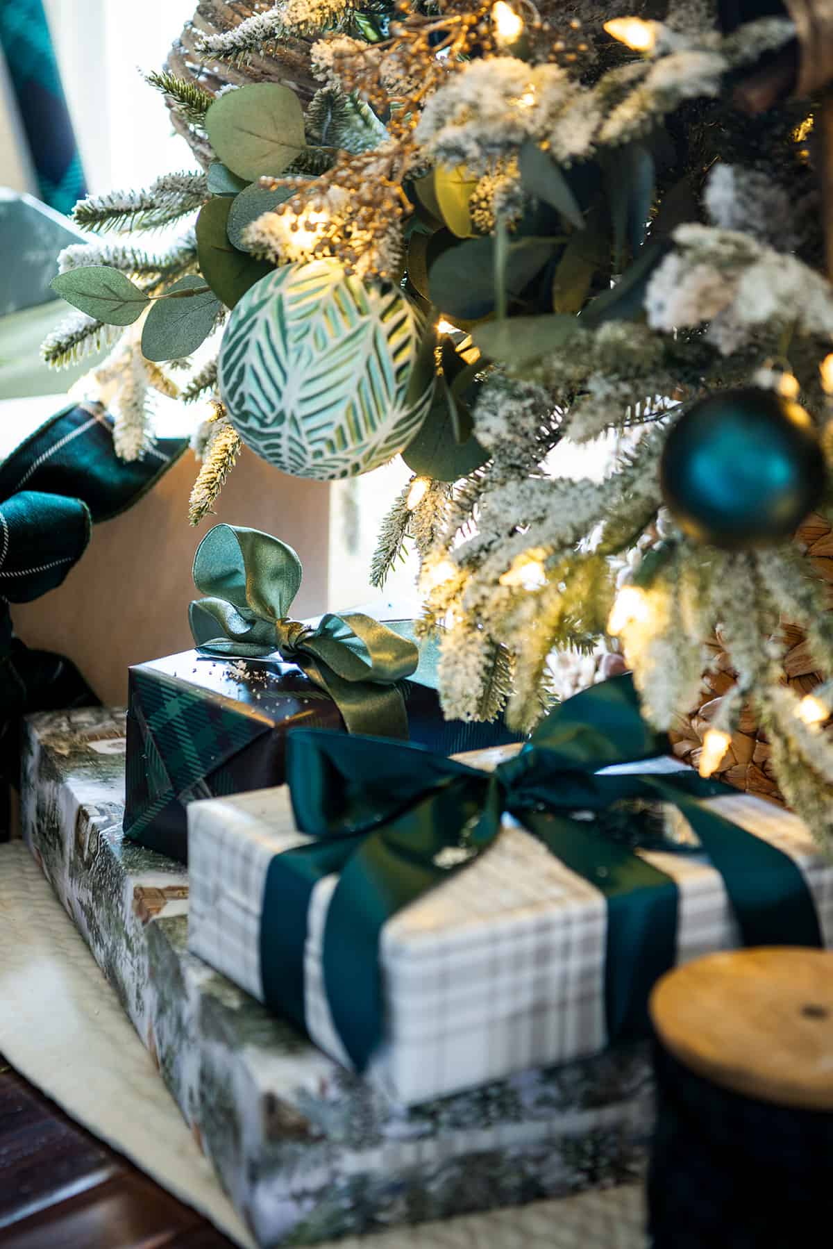 Green and gold Christmas decor with seafoam and dark green ornaments, green ribbon, frosted greenery, and coordinating wrapped gifts.