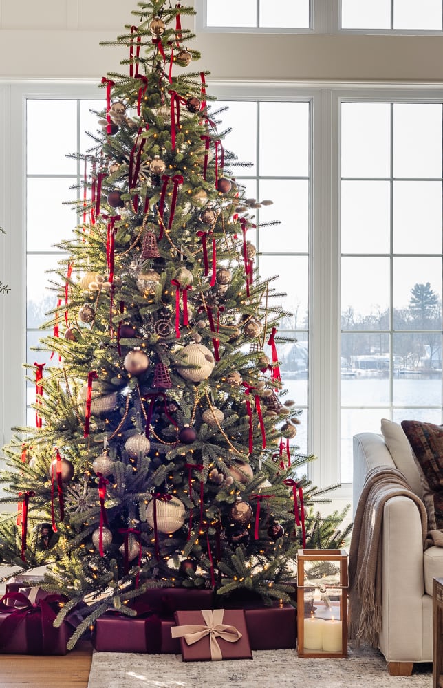 Burgundy and gold Christmas tree decorated with burgundy velvet ribbon, gold ornaments, warm white lights, and coordinating gifts.