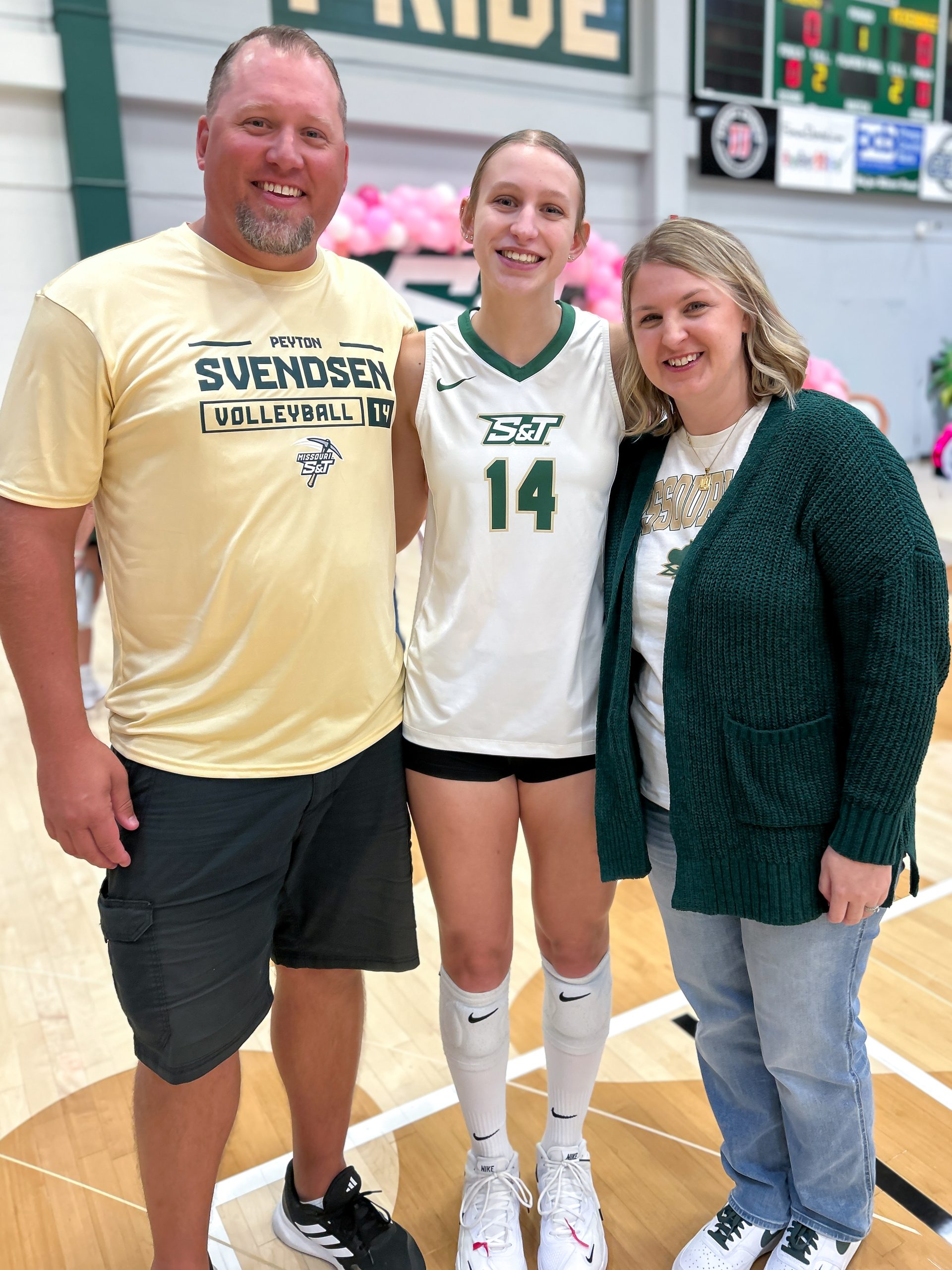 A college volleyball player poses with her proud parents after a Missouri S&T volleyball game.